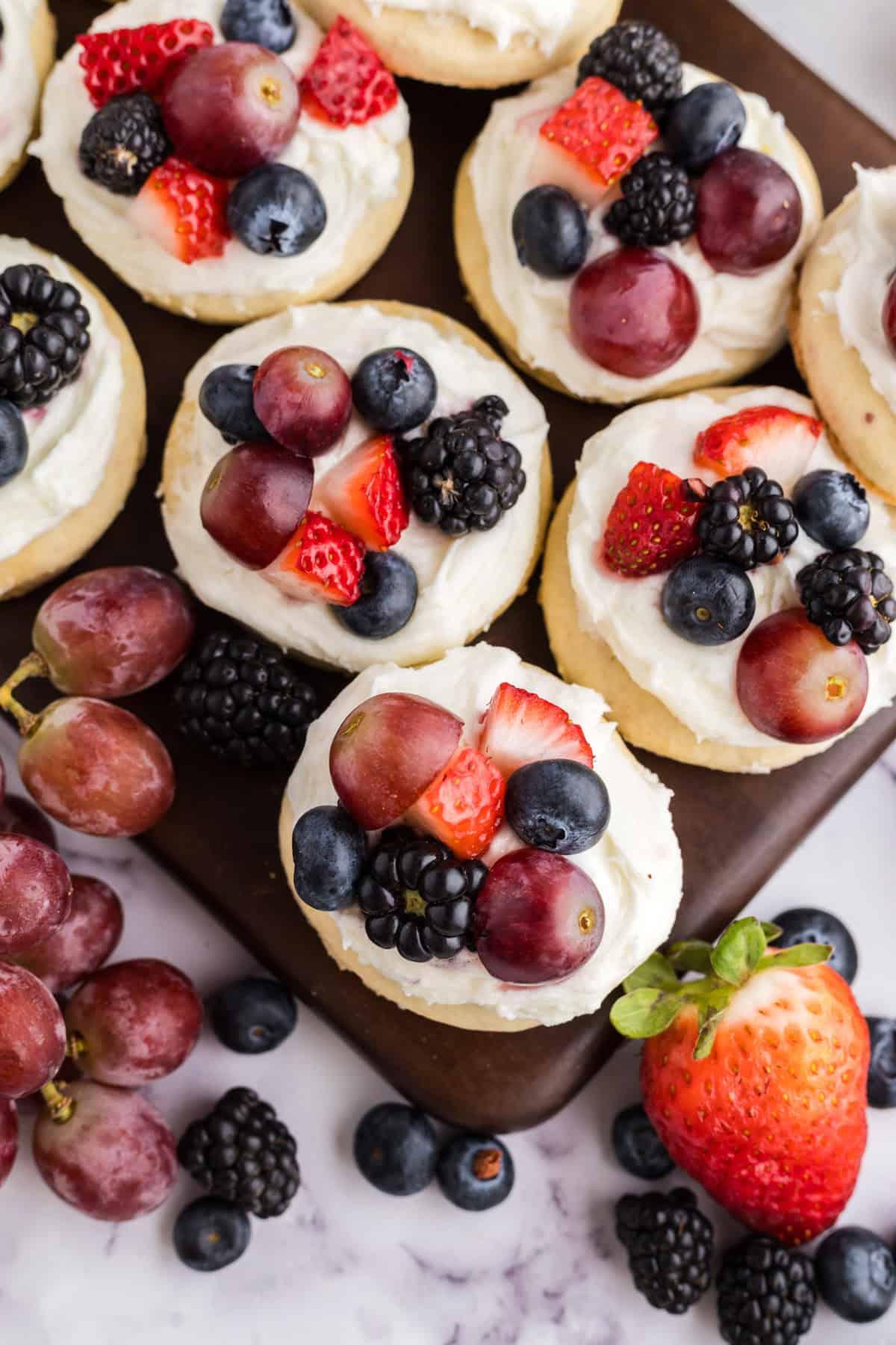 Μπισκότα Ζάχαρης Φρουτοπίζα 2 fresh fruit atop fruit pizza cookies on a wooden board.