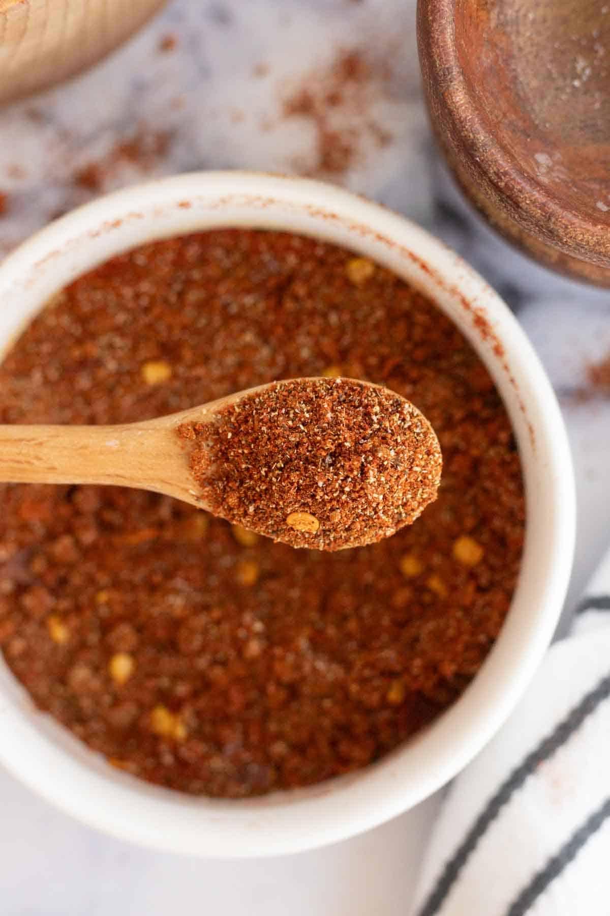 Καρύκευμα Αντόμπο 2 top view of a small white dish of adobo seasoning and a small wooden spoon