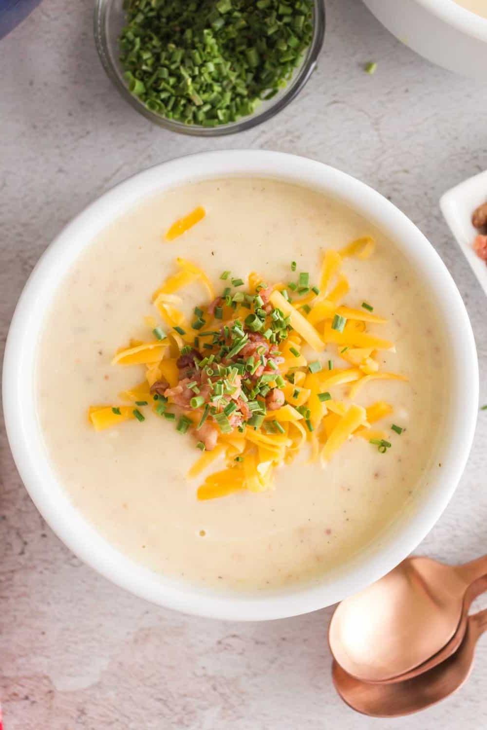 Κρεμόσουπα πατάτας 2 top view of a bowl of cream of potato soup with cheese bacon and chives on top