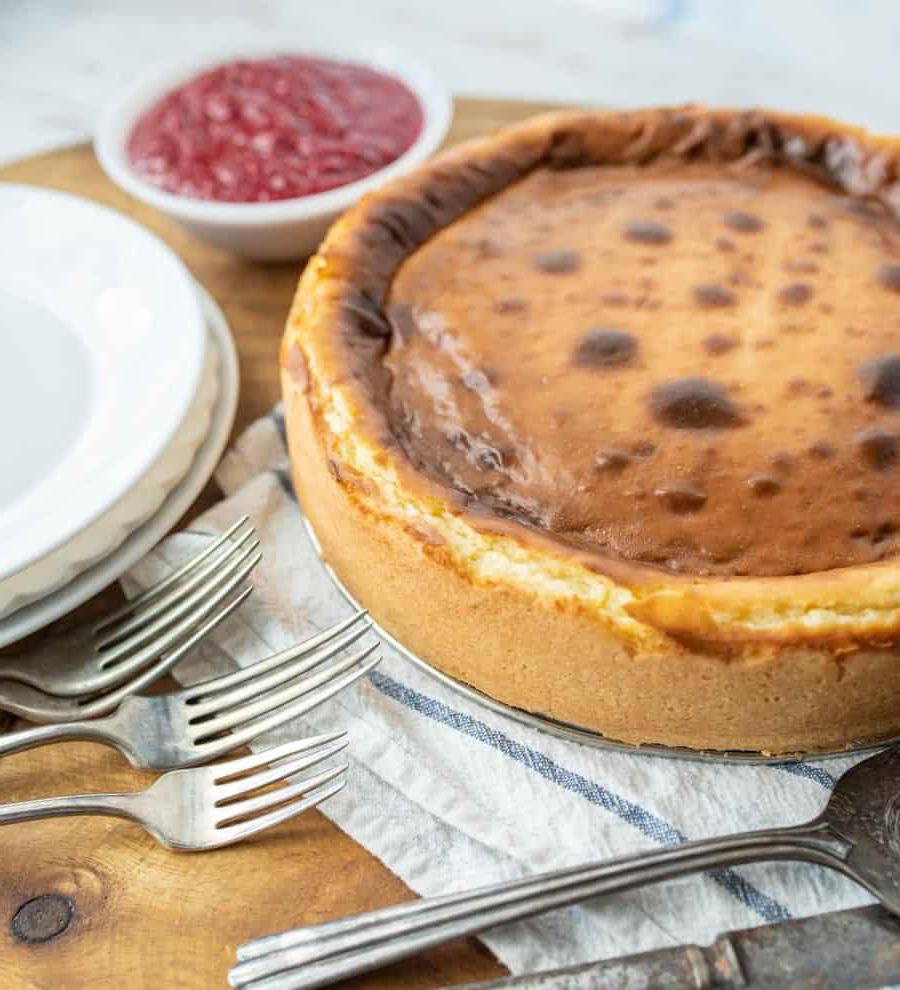 Τσιζκέικ της Μπεθ 3 Ένα άκοπο cheesecake δίπλα σε πιάτα και πιρούνια.