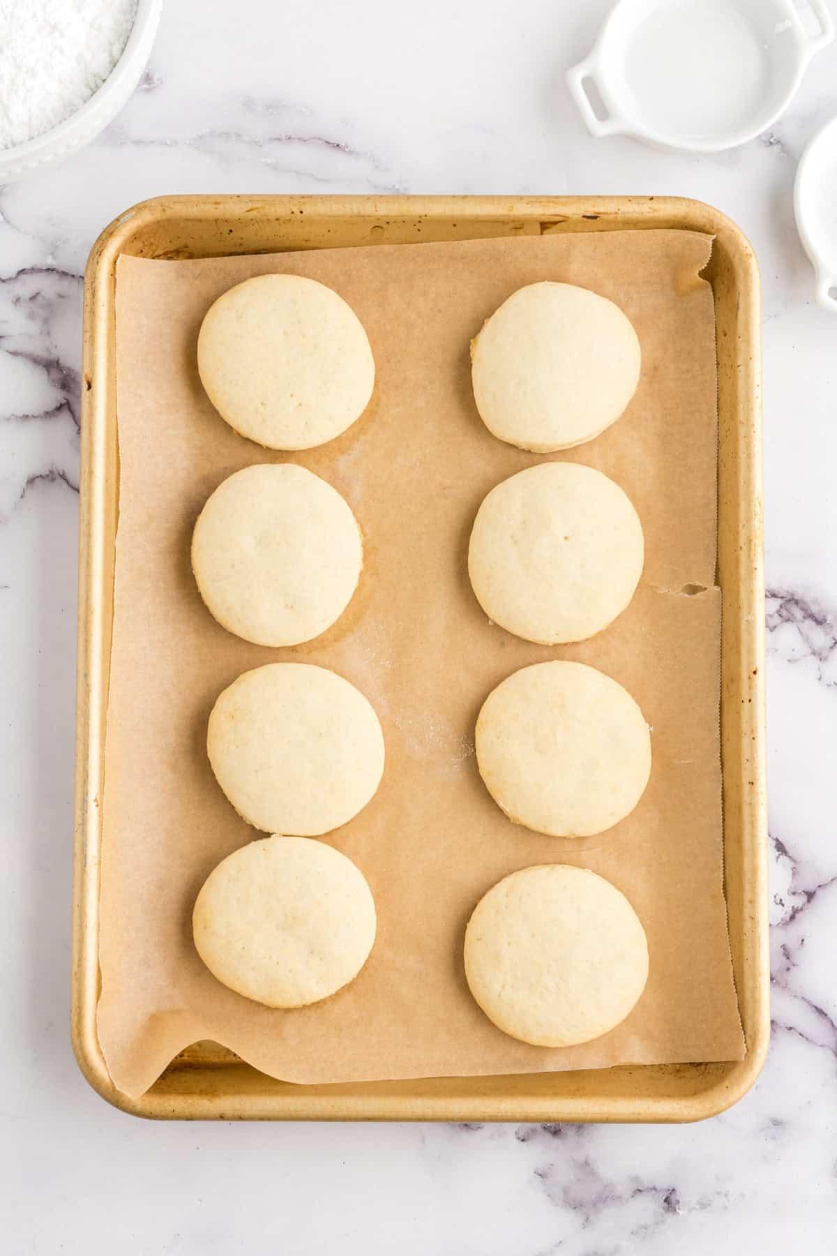 Μπισκότα Ζάχαρης Φρουτοπίζα 8 fruit pizza cookies without any toppings on parchment on a half sheet pan.