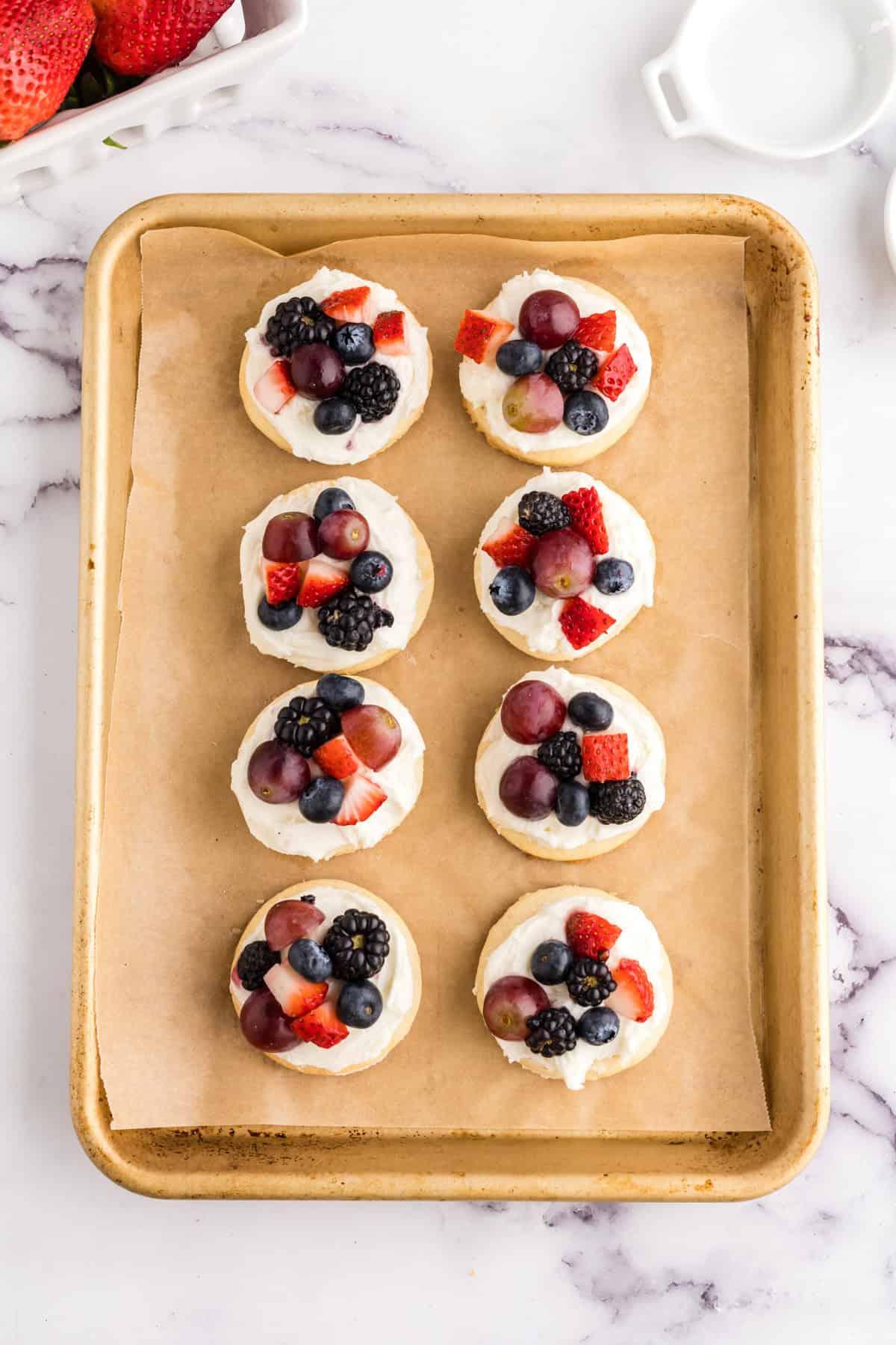 Μπισκότα Ζάχαρης Φρουτοπίζα 9 fruit pizza cookies on parchment on a half sheet pan.