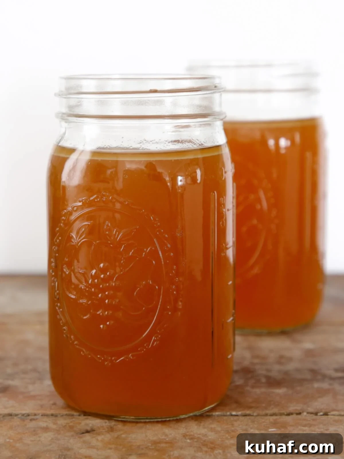 Two mason jars filled with golden chicken broth, ready for use or storage.