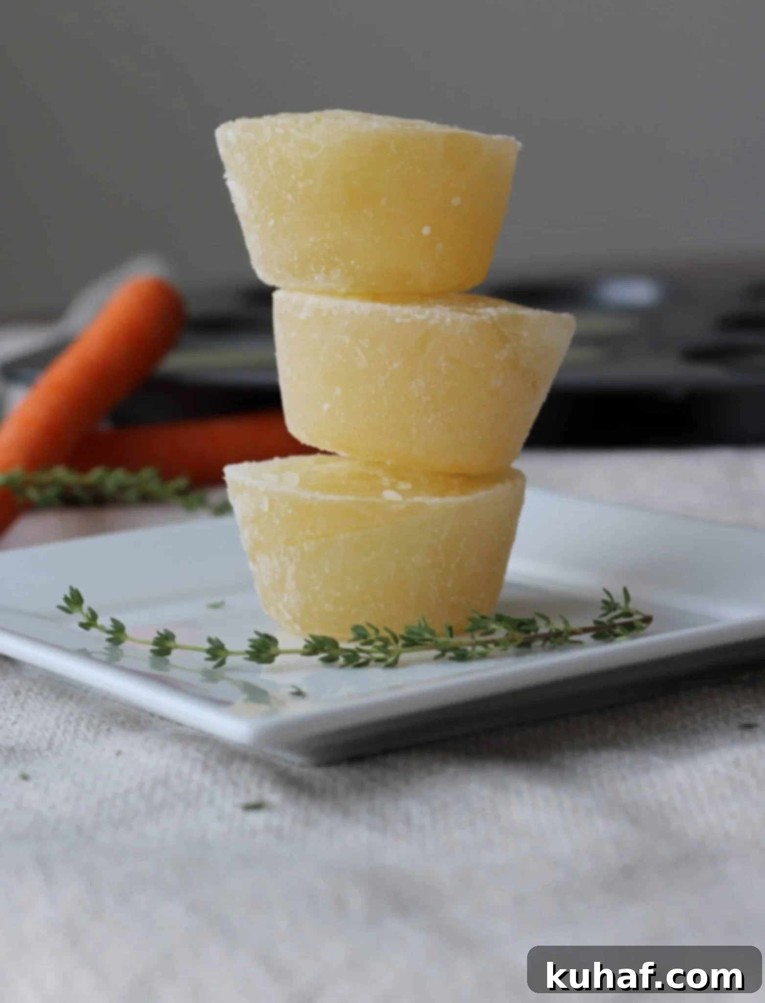 Homemade chicken broth frozen into convenient, cupcake-sized portions and stacked, ready for easy storage and thawing.
