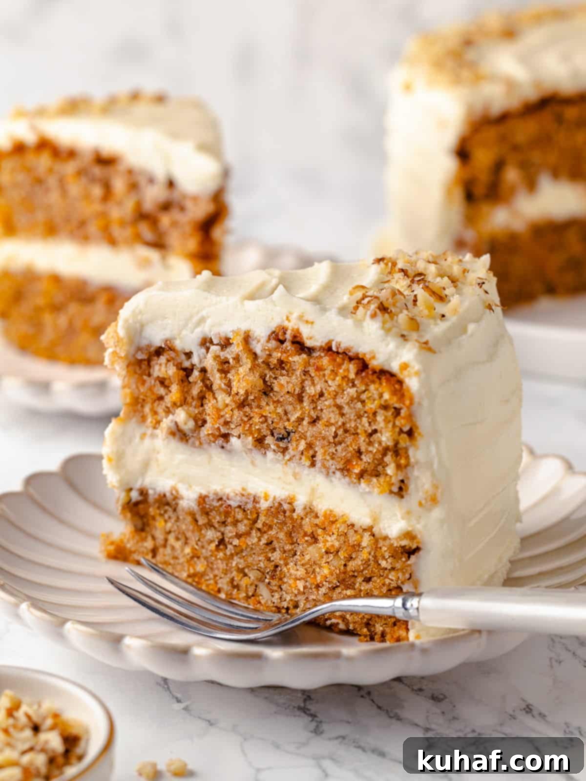 Interior view of slice of carrot cake with cream cheese frosting, showcasing its moist texture and rich carrot flecks.