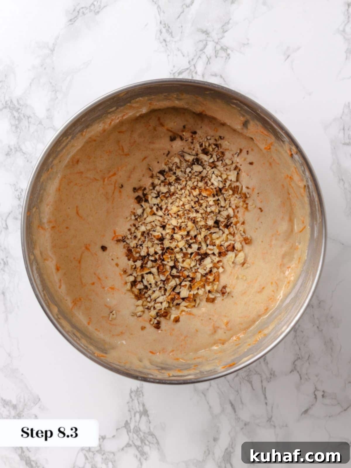 Toasted walnuts being folded into carrot cake batter.