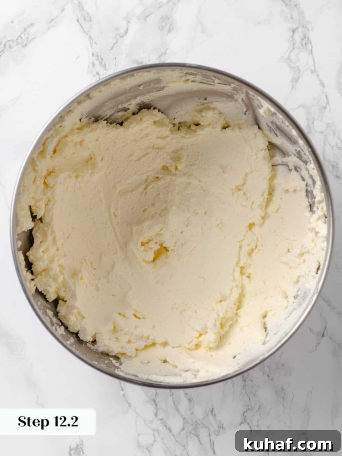 Frosting base visibly aerated and smooth after butter and cream cheese are beaten.