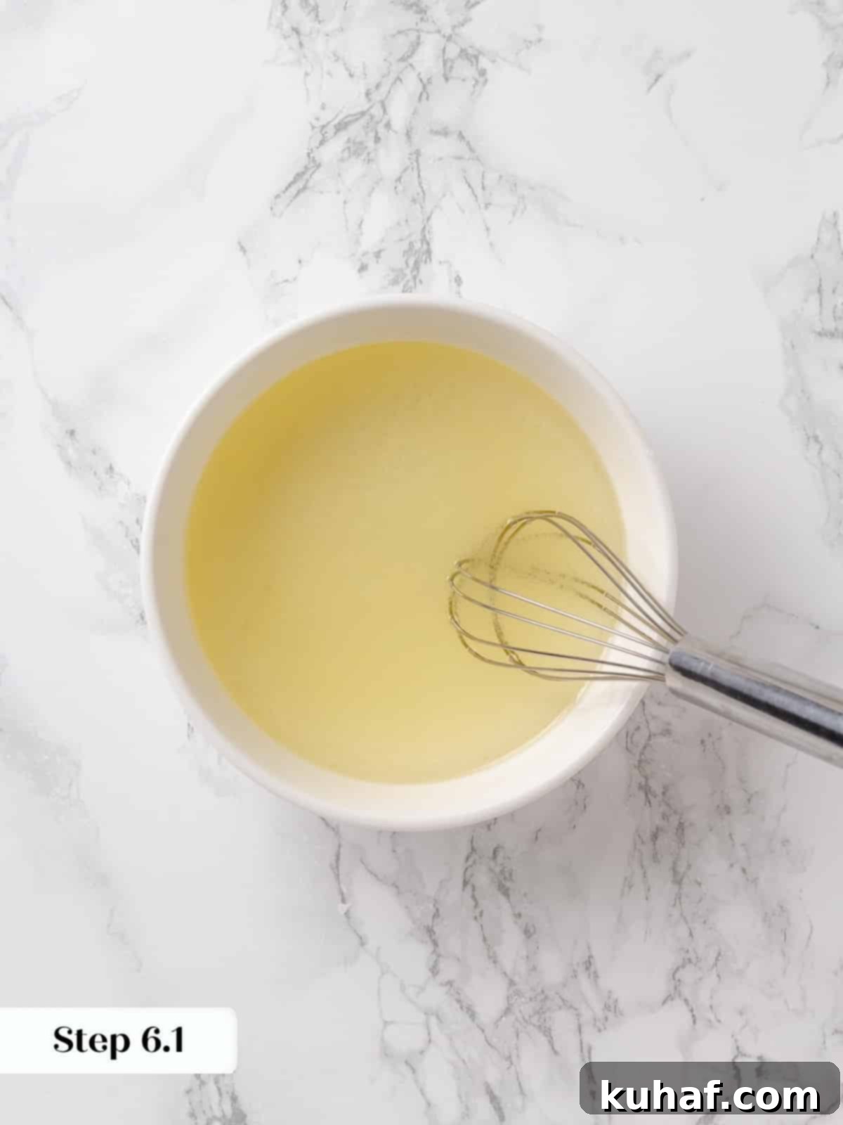 Lemon juice and vegetable oil whisked together in a glass container.