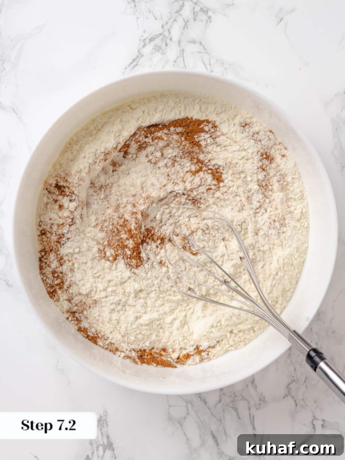 Gently mixing dry ingredients into whipped batter with a spatula.
