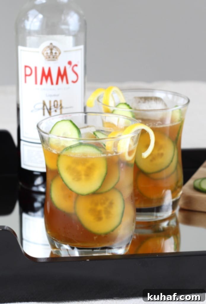 Cucumber Pimms Cooler 2 A tall glass of Cucumber Pimm's Cup garnished with cucumber slices and a lemon twist, ready for summer enjoyment.