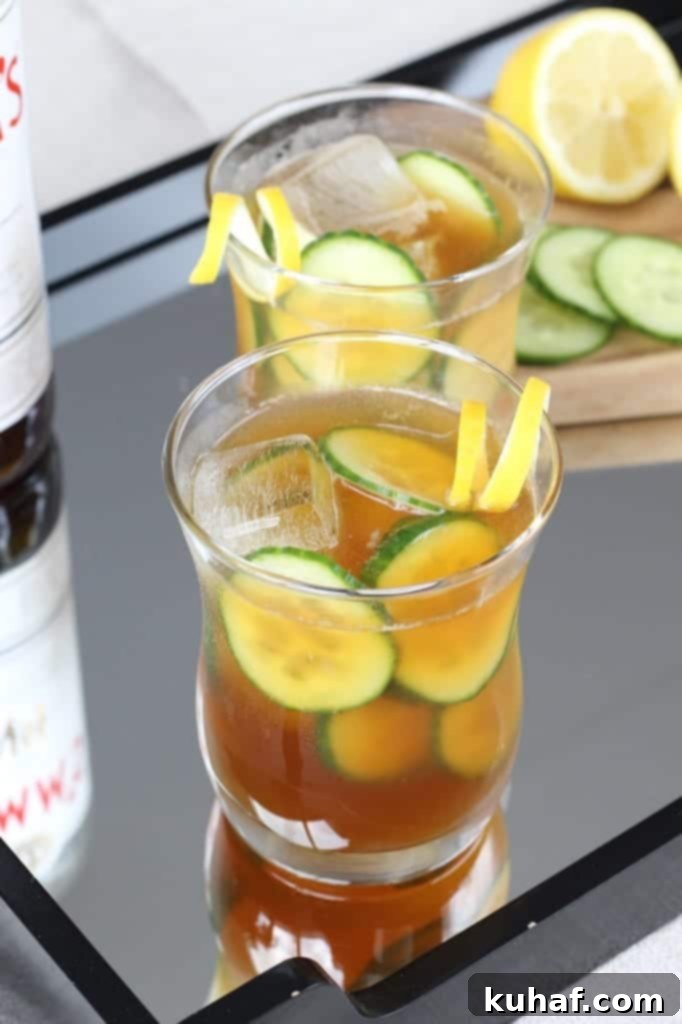 Cucumber Pimms Cooler 3 Close-up of a refreshing Pimm's Cup with ice, cucumber, and lemon slices, showing its inviting golden hue.