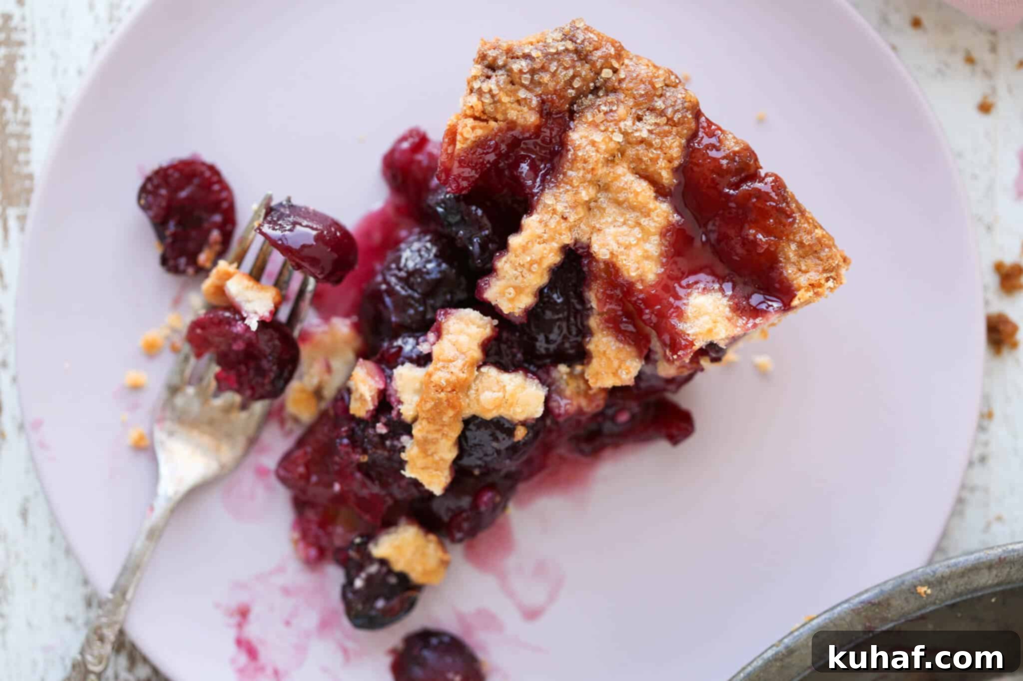 A perfectly baked Cherry Pie slice on a pink plate, showing its thick filling and flaky crust.