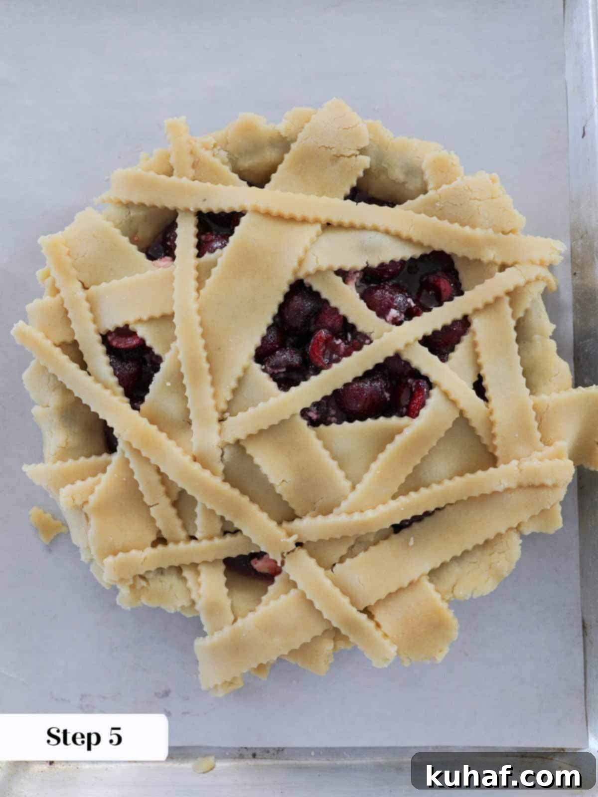 An unbaked cherry pie with an untrimmed top crust laid over the fruit filling, ready for shaping.