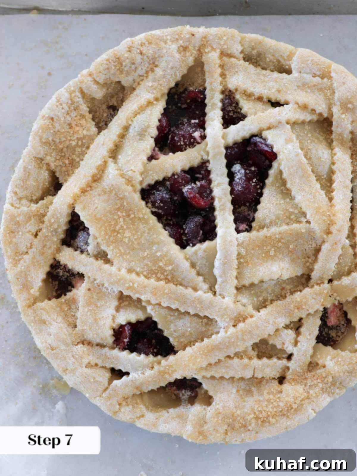 An unbaked cherry pie with a beautifully sugared top, ready for its journey into the oven.