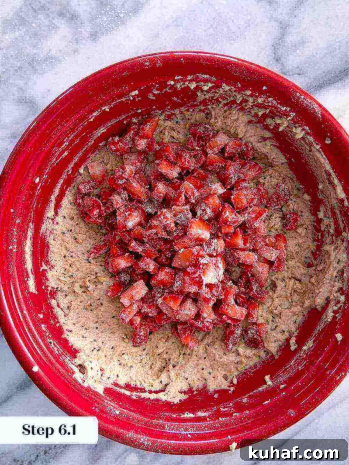 Delicious Strawberry Muffins 8 Freshly chopped strawberries, coated lightly in flour, being added to the prepared muffin batter in a large mixing bowl.
