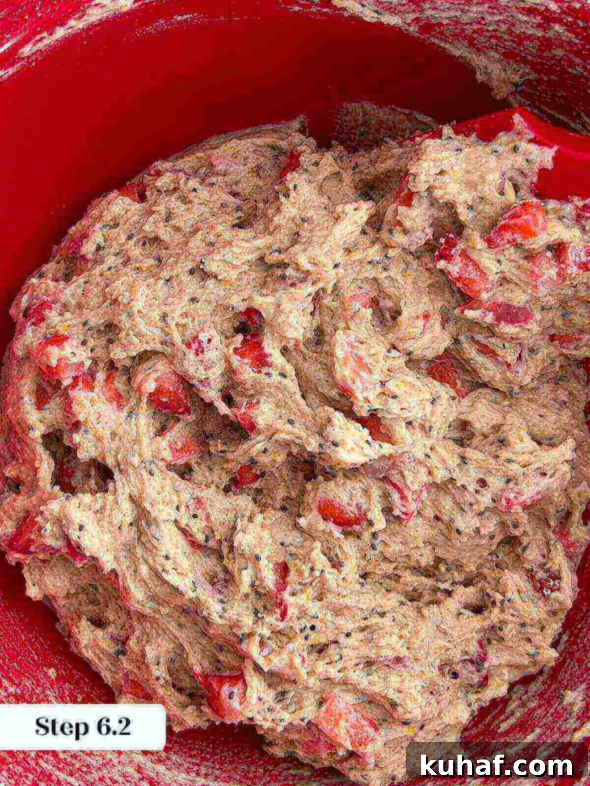 Delicious Strawberry Muffins 9 A rubber spatula gently folding fresh chopped strawberries into the muffin batter, ensuring even distribution.