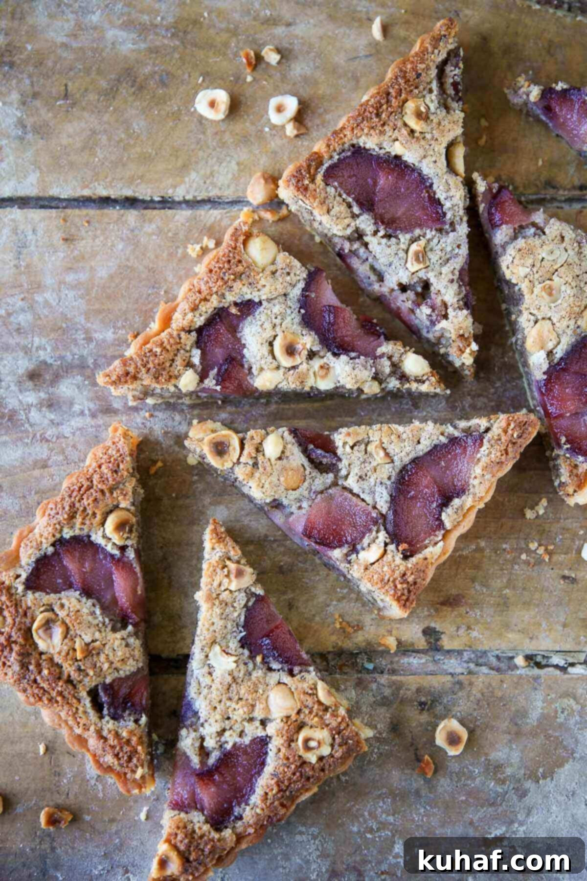 A beautifully baked hazelnut pear tart in a sweet tart crust, with a slice removed to reveal the exquisite filling and golden crust.