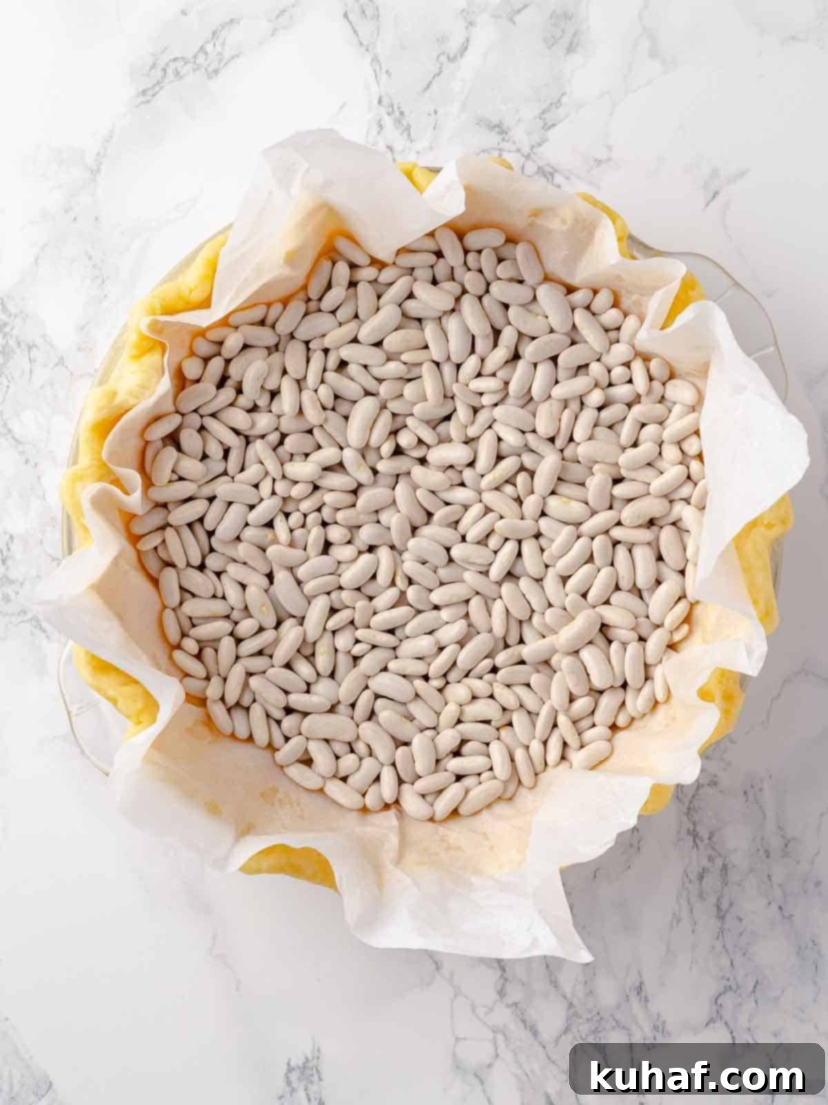 A Pâte Sucrée crust being blind-baked with baking beans, clearly showing the weights in place to prevent the dough from rising.