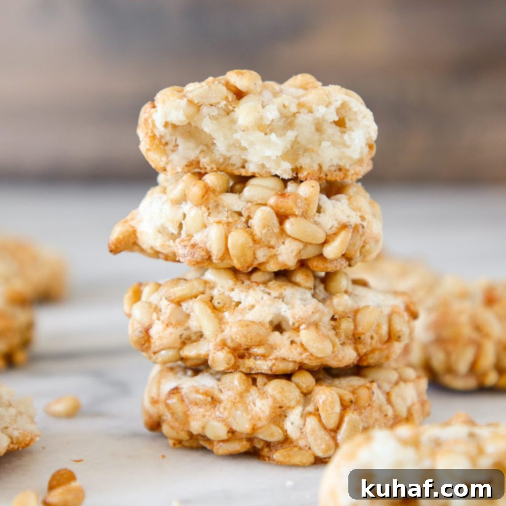 A stack of 4 pignoli cookies with their characteristic pine nut coating.