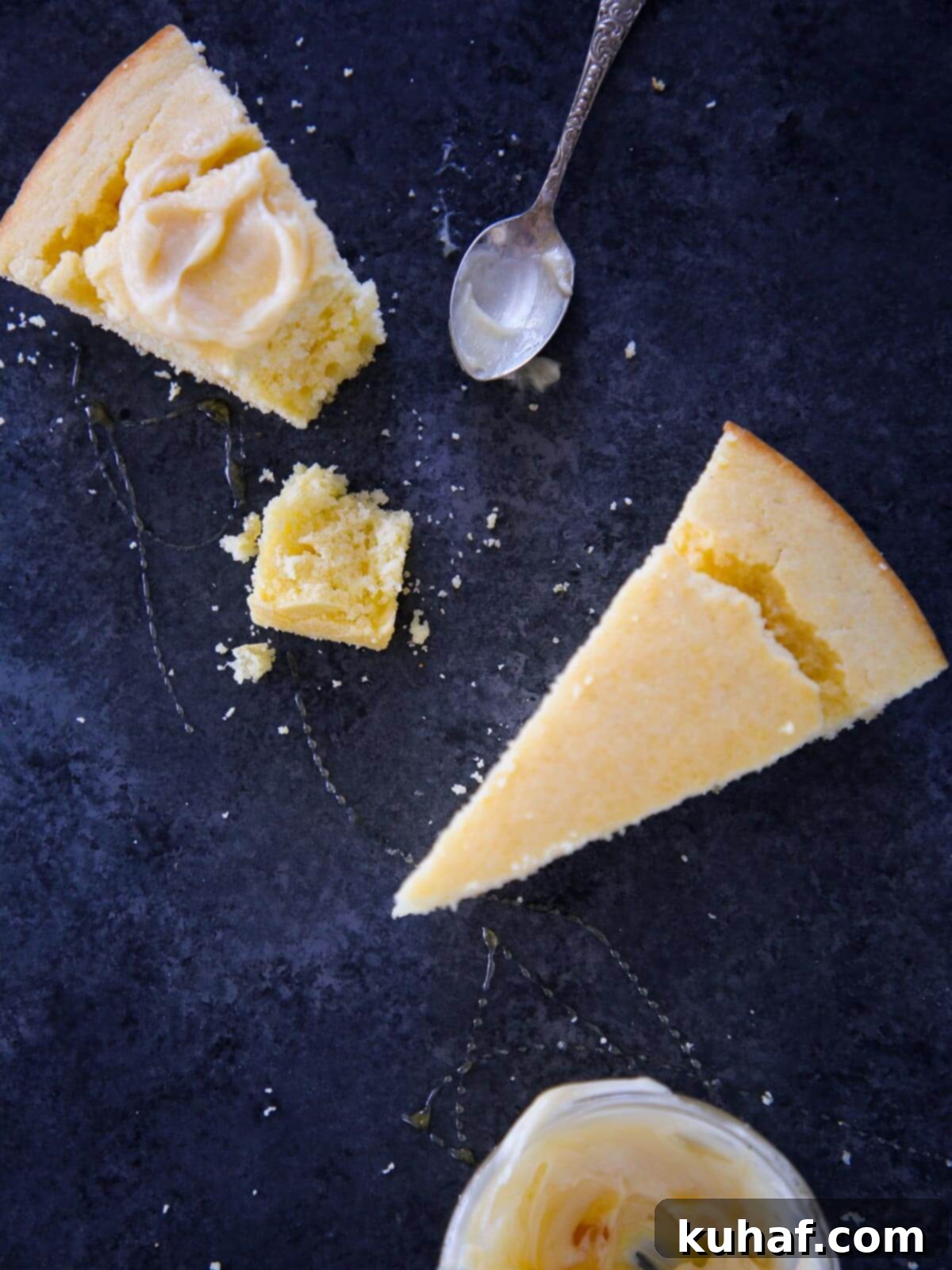 Two slices of golden Southern cornbread on a blue surface, topped with butter and a drizzle of honey.