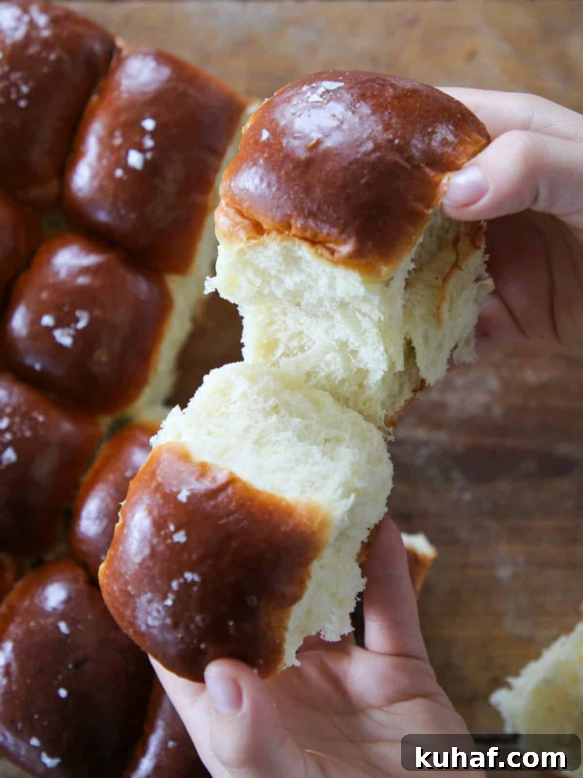 Pillowy Potato Rolls 2 Breaking a warm, fluffy potato roll by hand to reveal its tender interior.