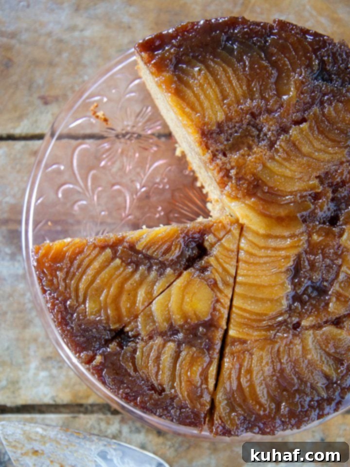 Pear upside down cake on clear cake stand, showcasing caramelized pears.