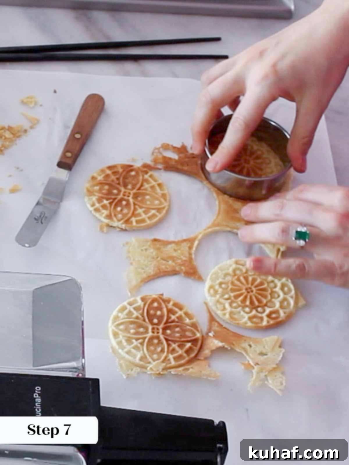 Cutting pizzelle cookies with a round cookie cutter on a cooling rack.