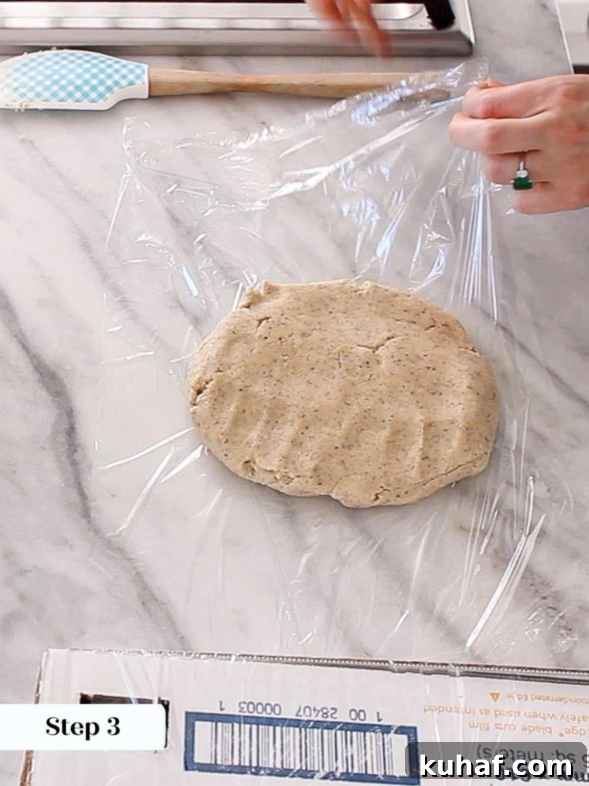 Dough being wrapped in plastic wrap for refrigeration.