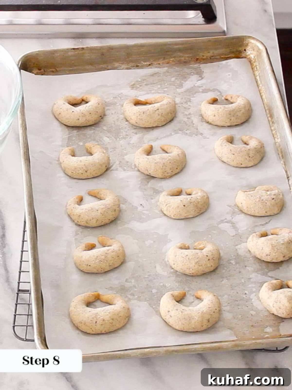 Baked crescent cookies cooling on a baking sheet.