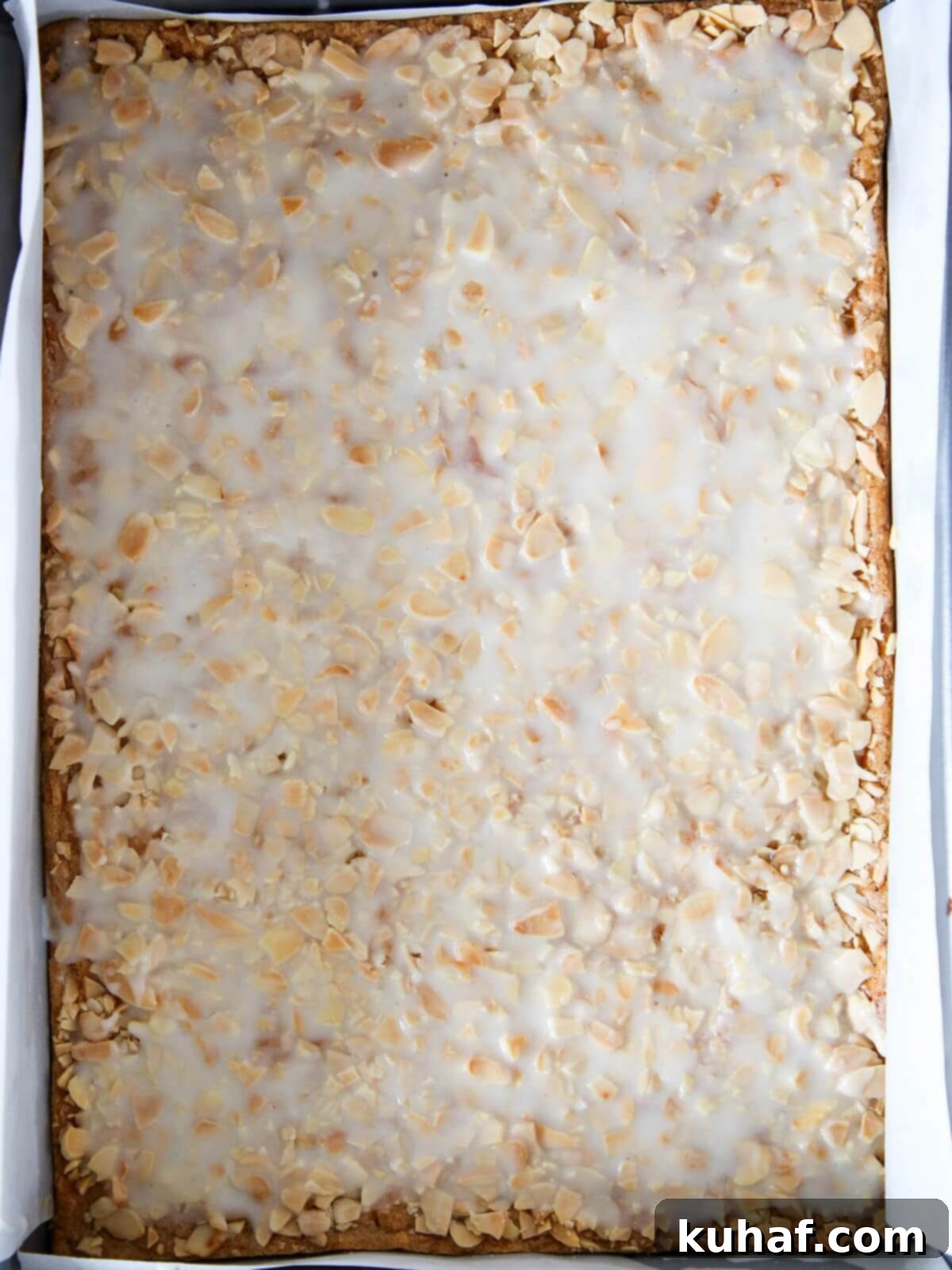White glaze perfectly spread over a pan of warm almond bar cookies.