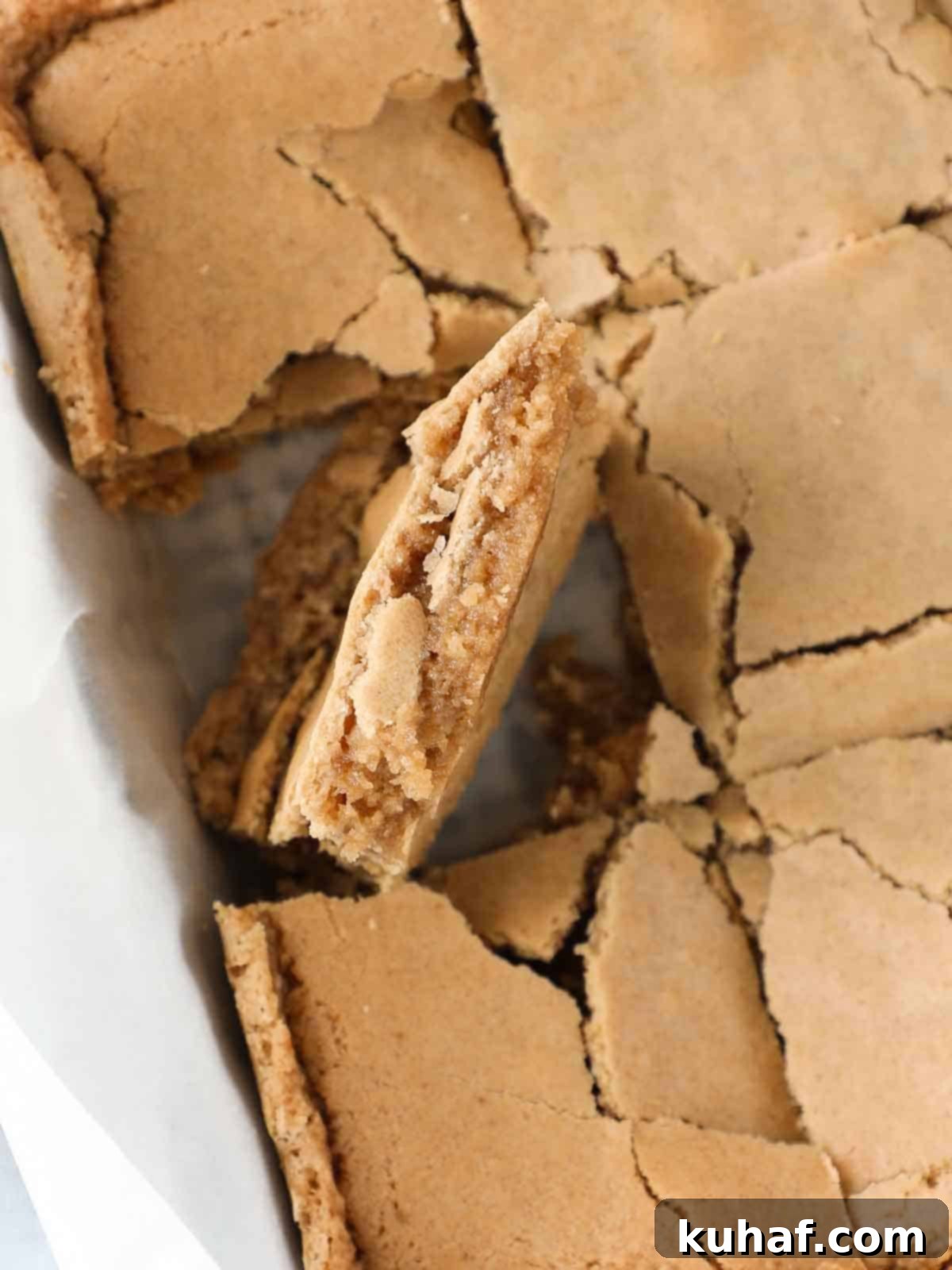 sliced butterscotch brownies in pan one brownie turned to view side.