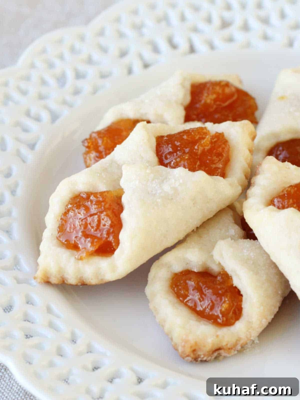 apricot kolacky cookies stacked on white lace plate.