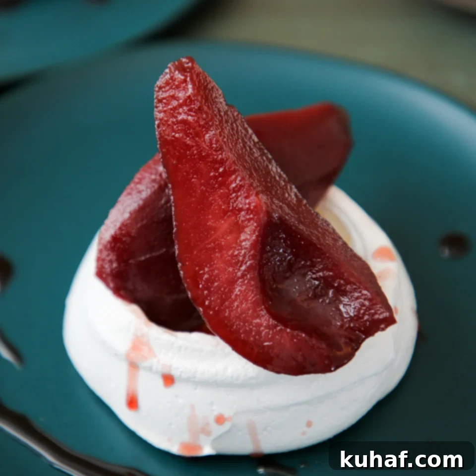 Poached Pear Pavlova, showcasing the delicate meringue with vibrant red wine poached pears.