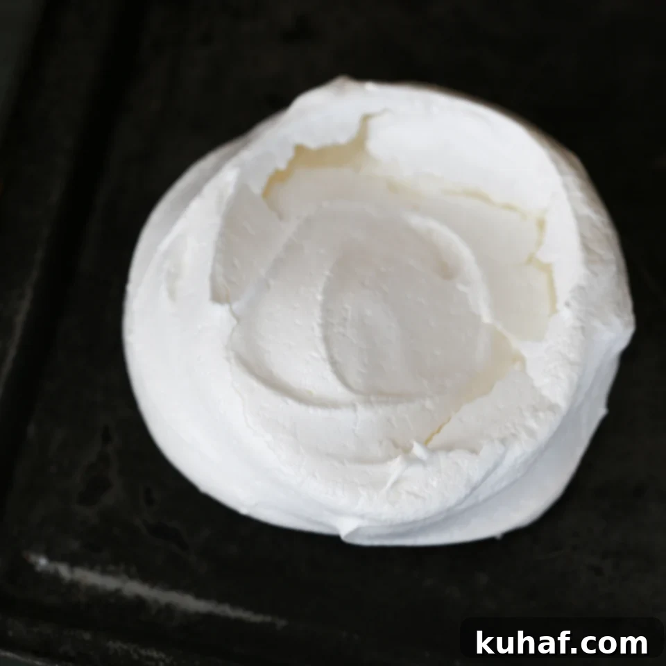 A close-up of a single Poached Pear Pavlova, showing its fluffy center.