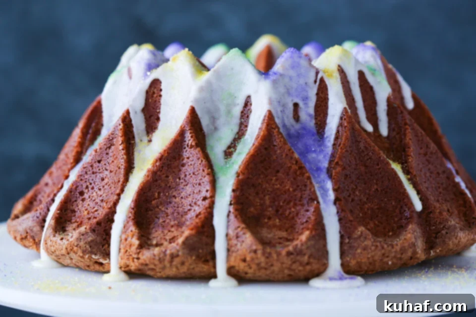 A hand carefully drizzling a generous amount of Bourbon glaze over the intricate design of a Mardi Gras Bundt Cake.