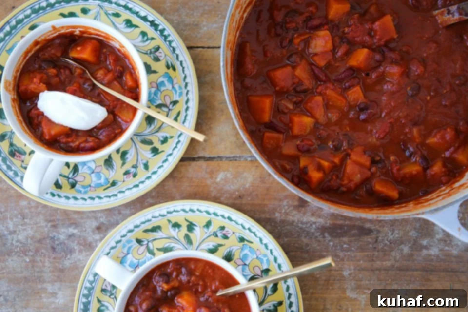 Two bowls of vegan chili garnished with fresh herbs, alongside the Dutch oven.