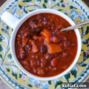 Butternut Squash Chili Vegan in white bowl, garnished with fresh herbs.
