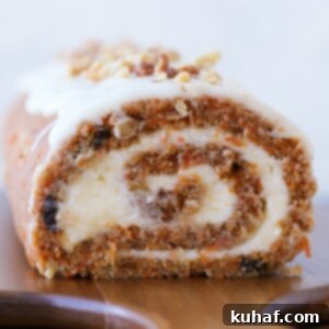 carrot cake roll with cream cheese buttercream on wooden board.