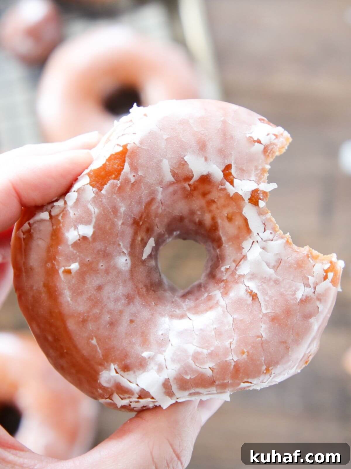 A hand holding a Krispy Kreme donut, ready to be enjoyed.
