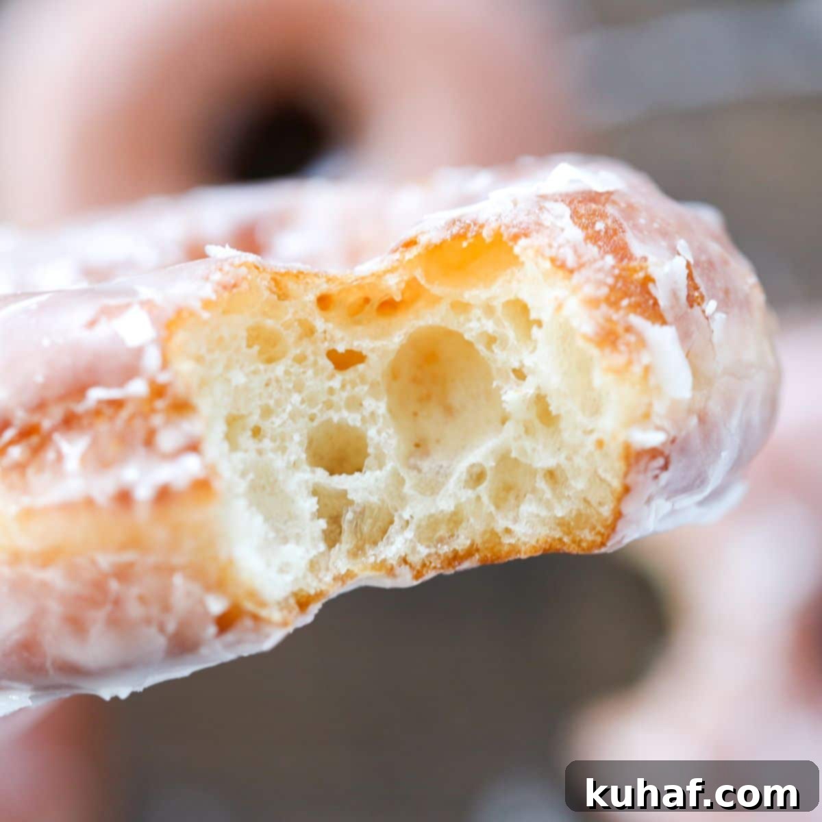 A Krispy Kreme donut with a bite taken out, showing its soft interior.