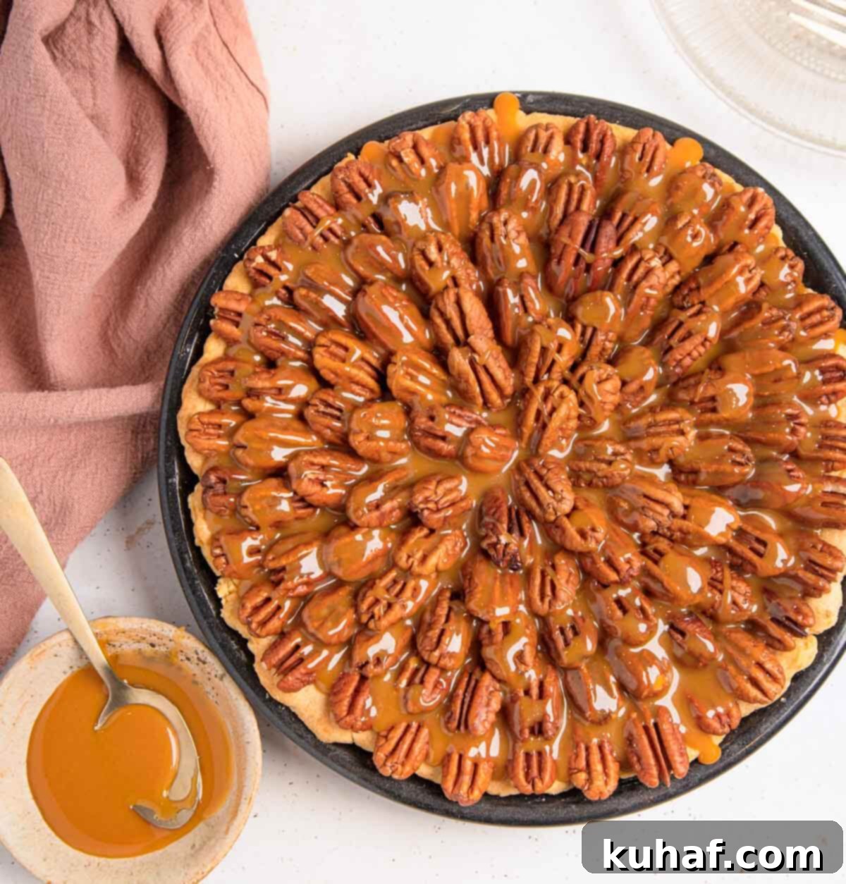 A whole chocolate pecan pie generously drizzled with glistening salted caramel sauce, adorned with toasted pecan halves.