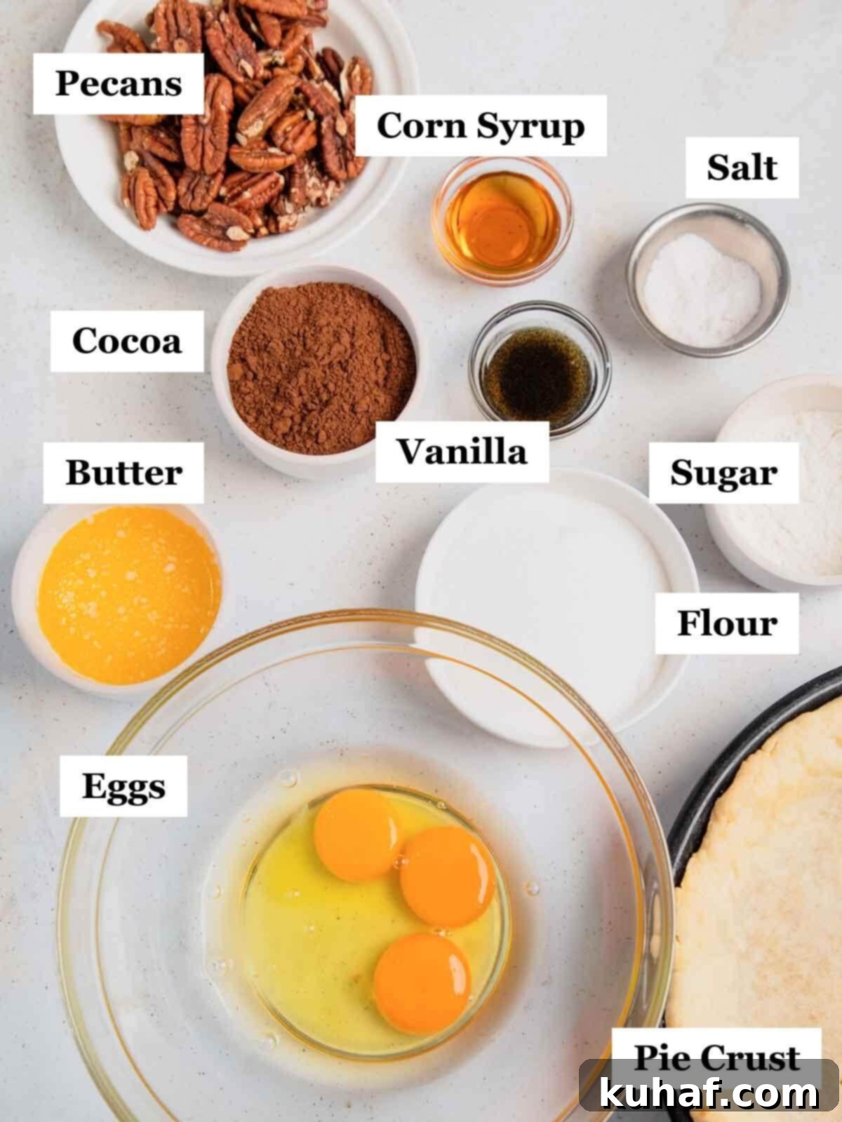 A selection of high-quality ingredients for chocolate pecan pie, including butter, eggs, flour, sugar, and pecans, thoughtfully arranged on a kitchen countertop.