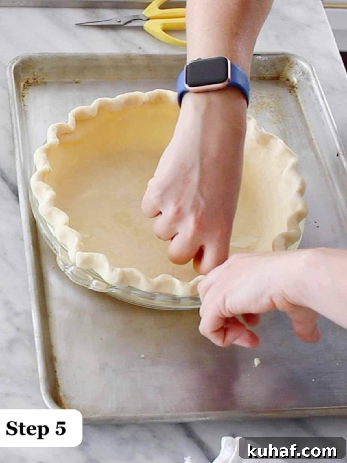 Step 5: Expertly fluting a pie crust around the rim of a tin, creating a decorative edge.