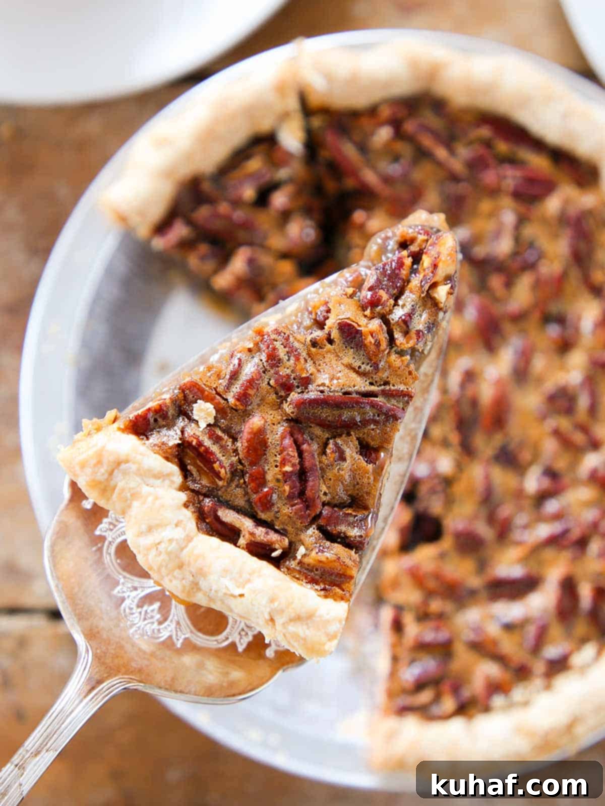 slice of pecan pie on pie server over whole pie.