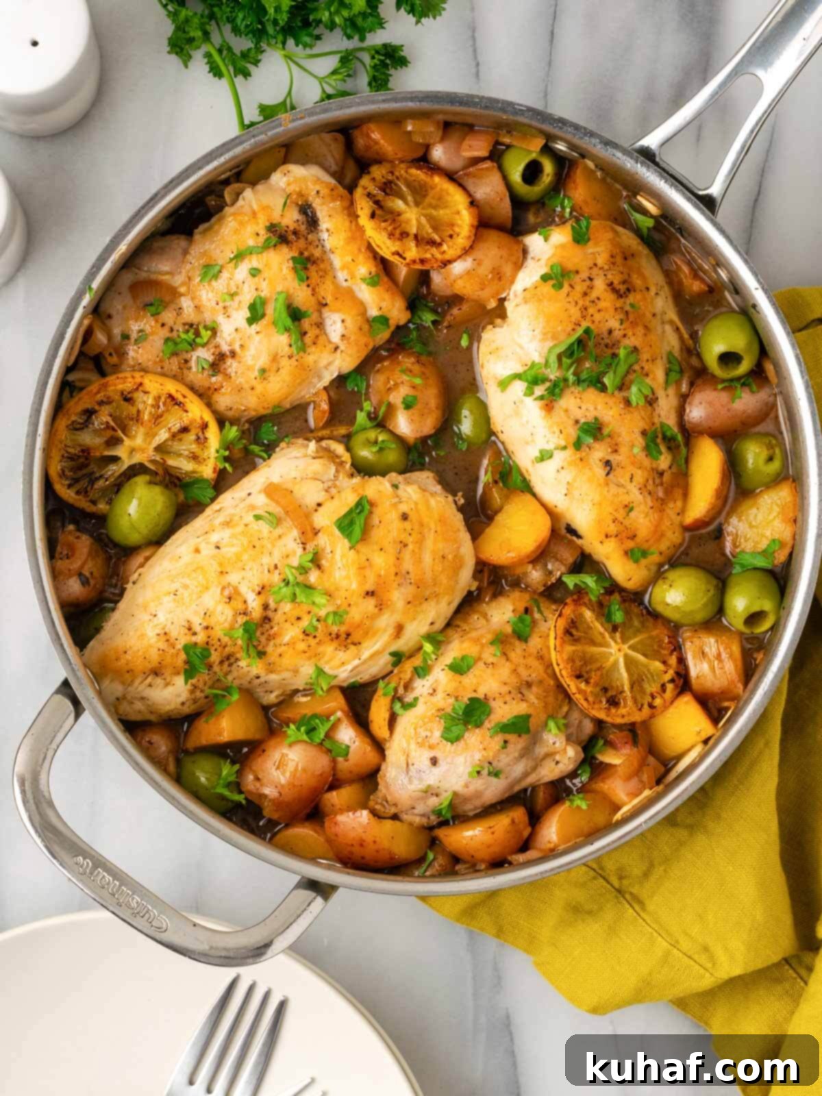 Bright and Tangy Lemon Chicken 2 Lemon chicken and potatoes in a pan, garnished with fresh parsley on a marble countertop.
