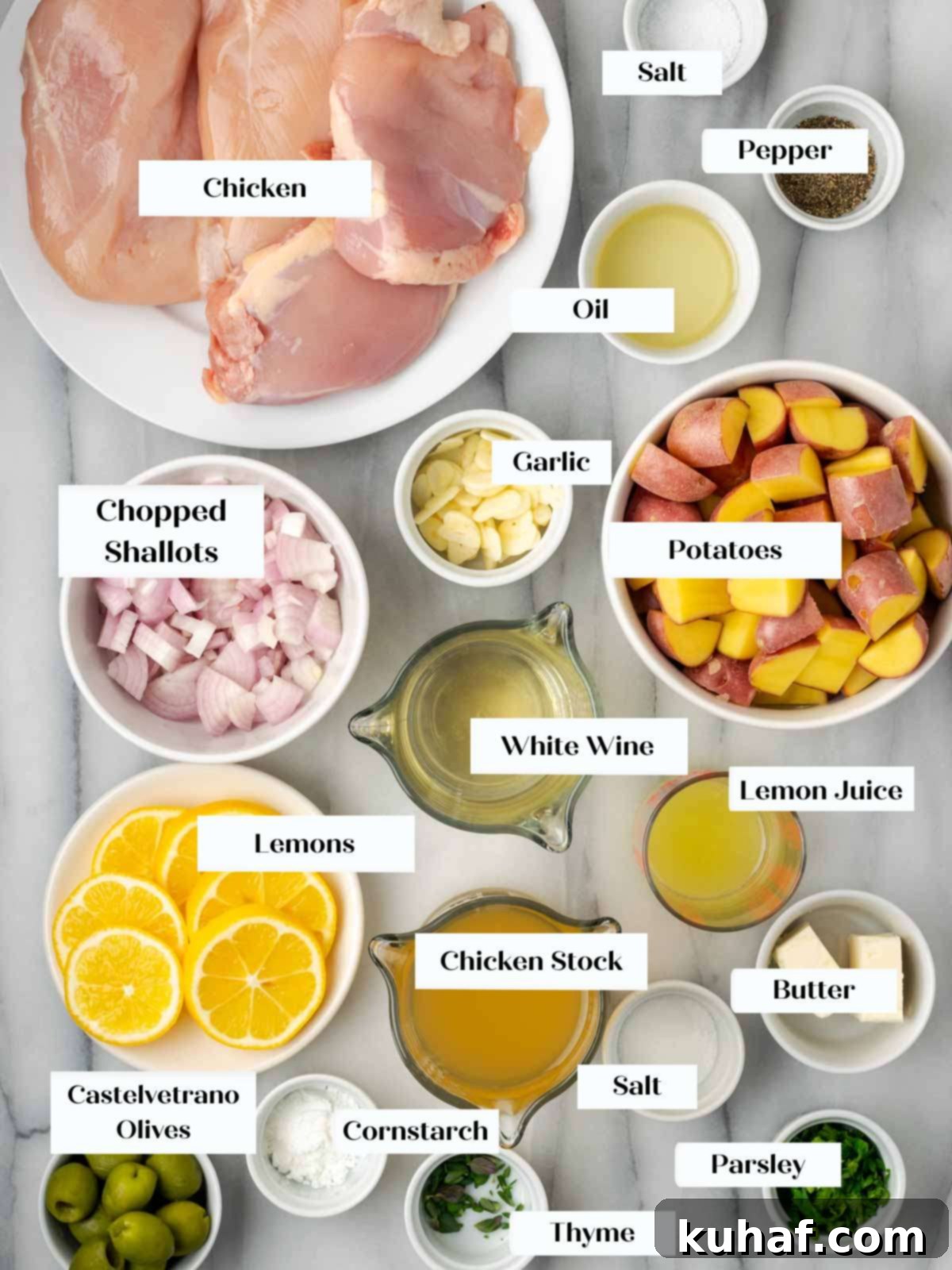 Bright and Tangy Lemon Chicken 4 A selection of fresh ingredients for lemon chicken arranged on a marble surface: chicken, lemons, herbs, potatoes, and shallots.