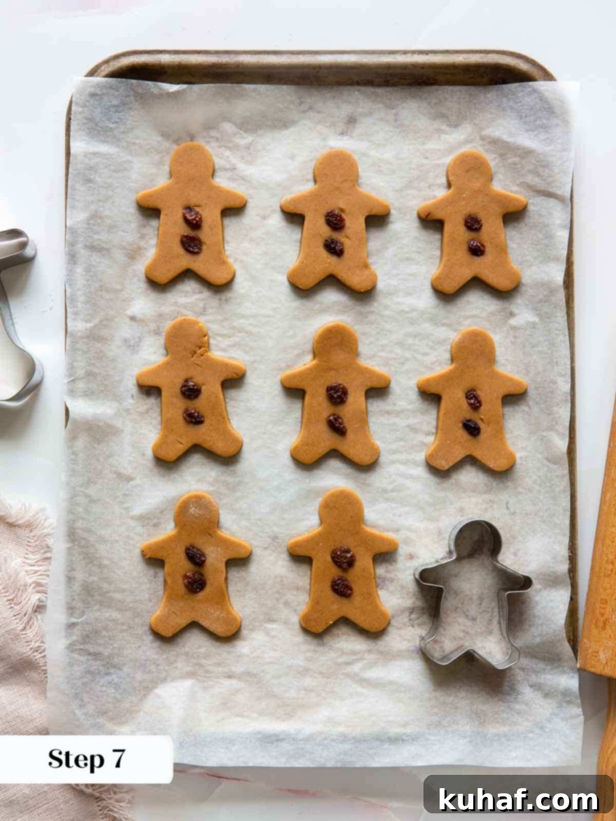 Decorating gingerbread men with raisins to create festive faces before baking.