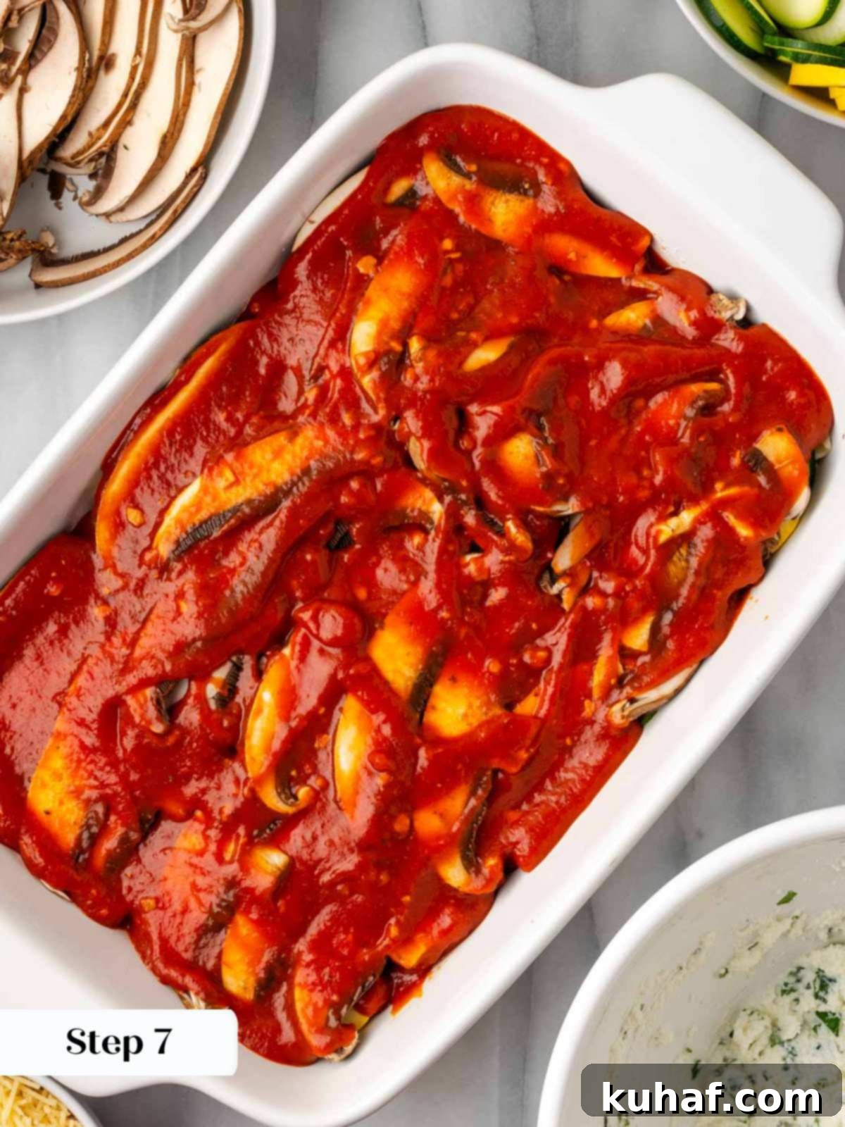 A layer of rich tomato pasta sauce spread over the vegetables in the lasagna dish.