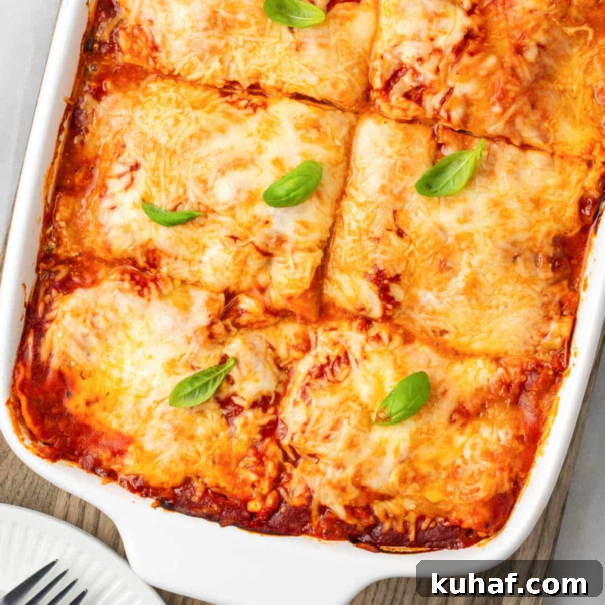 A close-up shot of a baked vegetable lasagna, showing the golden-brown melted cheese and the distinct layers of vegetables beneath.