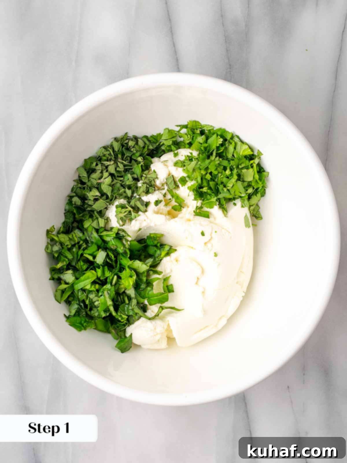 A bowl of ricotta cheese mixed with fresh green herbs.